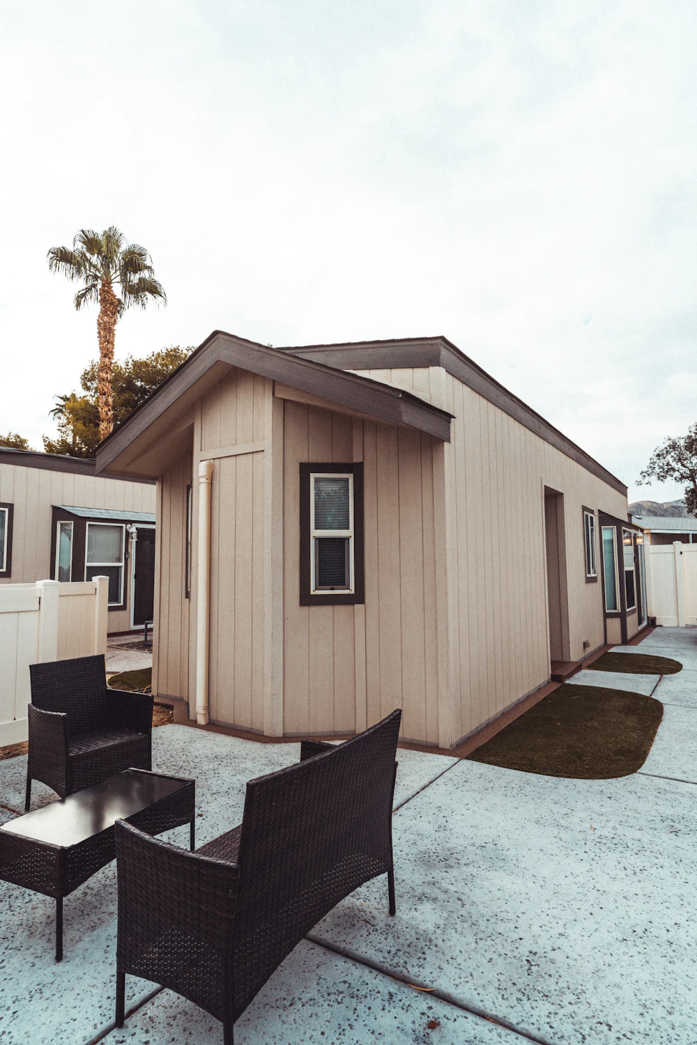 Small single wide mobile home with wood siding and patio